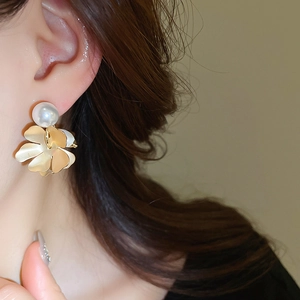 Detail of vintage gold flower earrings with white freshwater pearls worn by a model