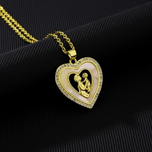 Detail of gold heart pendant with mother and child motif and sparkling zircon inlay