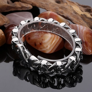 Detailed close-up of retro gothic skull steel bracelet with embossed relief on wooden blocks