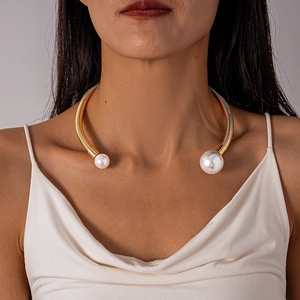 Detail of gold metal spring collar necklace featuring two elegant white pearls on model