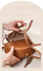 Portable brown leather jewelry case being placed into a handbag for travel storage