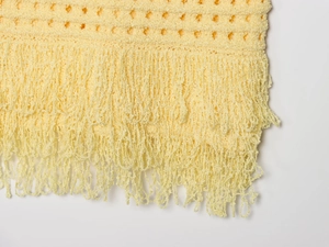 Gros plan détaillé sur la texture tricotée jaune et les franges élégantes à pompons