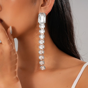 Close-up of rectangular crystal tassel earrings on a model with elegant light reflections