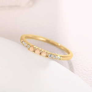 Makroaufnahme von Goldring mit rosa Opalen und funkelnden Zirkonsteinen im Detail