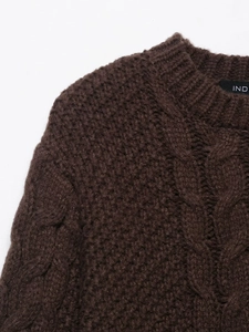 Close-up of dark brown round neck cable knit sweater with detailed texture and brand label