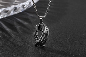 Gros plan d'un pendentif aile d'ange en acier inoxydable avec texture plume d'argent