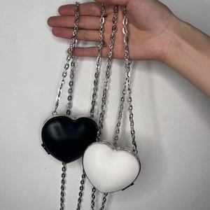 Detail of heart-shaped mini chain bags in black and white with silver metal trim