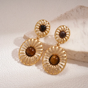 Close-up of vintage tiger eye earrings with golden radial design on textured stone