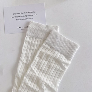 Detailed view of white ribbed high-density knit socks with elegant vertical textures
