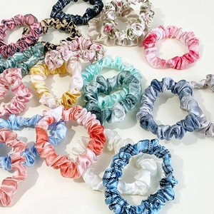 Assorted satin silk scrunchies in various floral and plaid patterns for hair styling