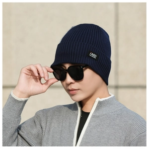 Close-up of a navy blue ribbed knit beanie featuring a stitched woven brand label