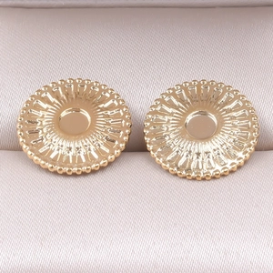 Macro detail of golden circular stainless steel earrings with textured radial patterns