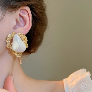 Gros plan d'une boucle d'oreille vintage triangle et perle avec texture dorée sur modèle
