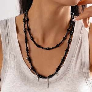 Close-up of double-layered black beaded necklace with silver cross and cone pendants