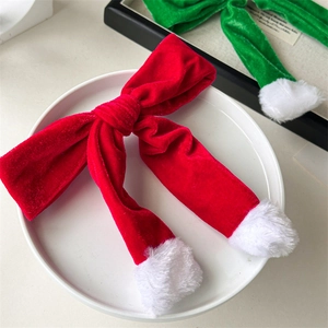 Detail of red velvet Christmas bow hair clip with white faux fur trim on white plate