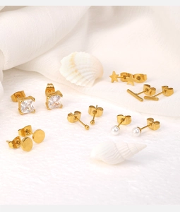 Close-up of 18K gold-plated earring set with zircon, pearl and star shapes on a white surface