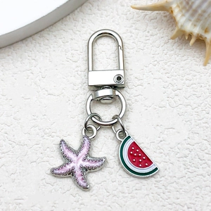 Macro detail of alloy enamel keychain featuring a pink starfish and watermelon charm