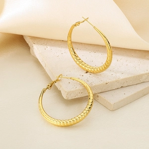 Classic gold textured hoop earrings with striped croissant design on a luxury backdrop
