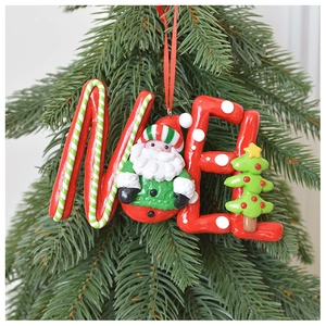 Detailed close-up of a Santa and Christmas tree clay hanging ornament on a green pine tree
