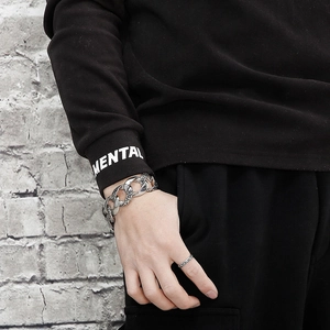 Detail of silver snake-pattern Cuban chain bracelet and ring worn on a male hand