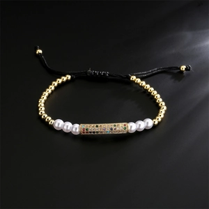 Detailed close-up of a braided cord bracelet with gold beads and a colorful zircon bar