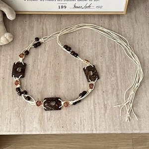 Detail of bohemian hand-woven waist belt with wooden beads and carved rose floral charms