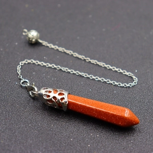 Orange hexagonal crystal point pendulum necklace with silver chain on a dark textured base