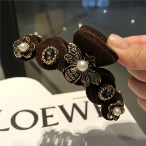 Détail de la pince à cheveux en velours marron avec abeille dorée, fleurs et perles