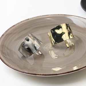 Detail of gold and silver textured metal hair clips on a ceramic plate, wavy hammer pattern