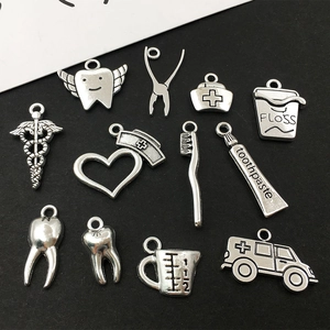 Makro-Detail von 12 silbernen Zahnarzt-Metallanhängern mit Zähnen und medizinischen Tools