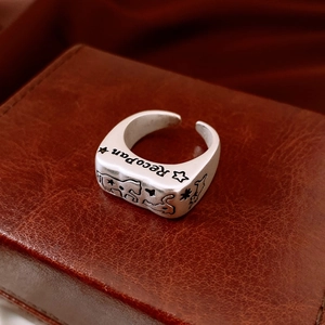 Macro shot of silver retro engraved ring with RecoPan lettering on brown leather