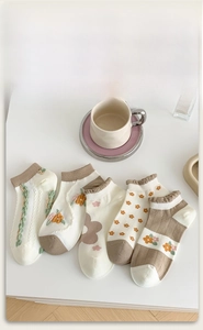 Close-up of five pairs of combed cotton socks in beige and brown tones with floral patterns
