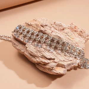Detail of silver tassel necklace with zircons and teardrop crystal on natural stone