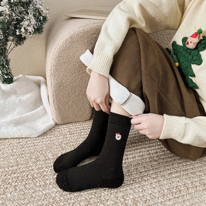 Gros plan de chaussettes de Noël noires avec broderie détaillée du Père Noël en coton doux