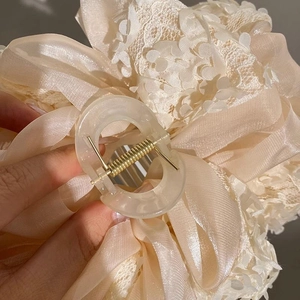 Détail d'une pince à cheveux avec nœud en organza multicouche à motif floral crème