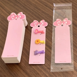 Pink hair clip display cards with cute bow designs on a rustic wooden background