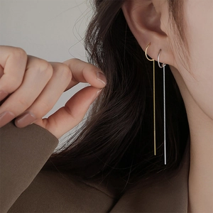 Minimalist long tassel ear threads in gold and silver finish shown on a female model