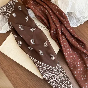 Vintage paisley silk scarves in coffee and caramel tones on a textured wooden background