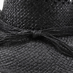 Détail de la texture de paille tressée noire et de la cordelette nouée sur le chapeau