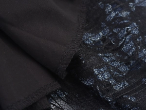 Détail de tissu noir élégant cousu avec de la dentelle fine et des motifs floraux bleus