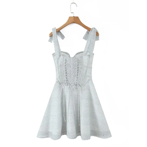Detail view of polka dot dress with adjustable bow tie shoulder straps on wooden hanger