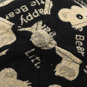 Macro shot of fine bear embroidery on black baseball cap with golden beige thread details