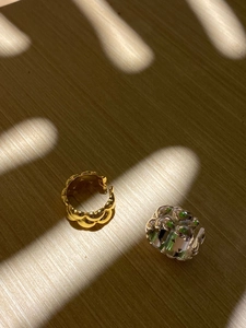 Detail of gold wavy band and silver ring with green enamel inlay on wood background