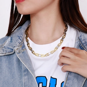 Close-up of two-tone gold and silver link chain necklace on model wearing a white tee
