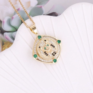 Detail of 18K gold leopard head pendant with green gemstones and zircon micro-paving