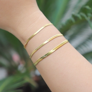 Three gold-plated stainless steel snake bone chains layered on a wrist for a modern look