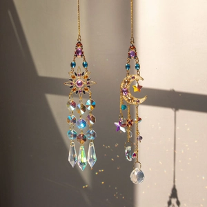Detail of sun and moon crystal suncatchers casting rainbow reflections on a white wall