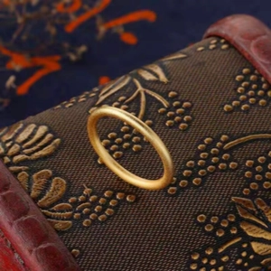 Macro detail of an elegant matte gold plain band ring featuring ancient heritage style