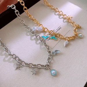 Detailed close-up of marine-themed necklaces featuring enamel fishtail and pearl charms