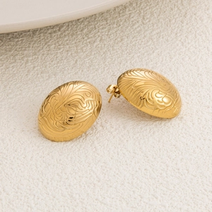 Macro shot of gold-plated stainless steel stud earrings with intricate embossed leaf texture